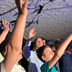 A group of people singing and raising their hands to the low, white brick ceiling.